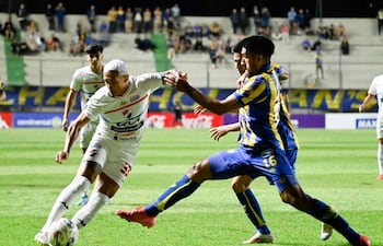El extremo de Nacional, Orlando Gaona Lugo intenta escapar del volante de Sportivo Luqueño, Ángel "Pirayú" Benítez.
