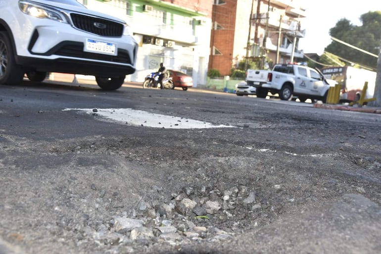Calle de Asunción con un bache profundo en el asfalto y vehículos de tránsito.