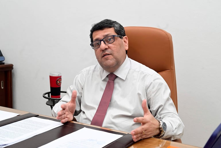 Juan Marcelo Estigarribia, con camisa blanca y corbata roja, expresa seriedad mientras gesticula en su oficina.
