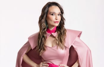 Lali González en atuendo rosa asimétrico, posando con confianza, fondo blanco que resalta su vestuario.