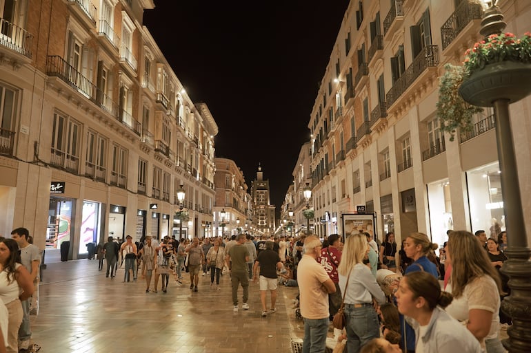 Turistas y lugareños caminando por la  calle Marqués de Larios por la noche, una famosa calle peatonal en el centro histórico de Málaga, España.