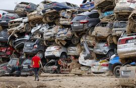 Un voluntario camina junto a una pila de vehículos destrozados en Paiporta, este martes. La DANA que dejó en Valencia más de dos centenares de muertos ha cambiado la vida de miles de personas.