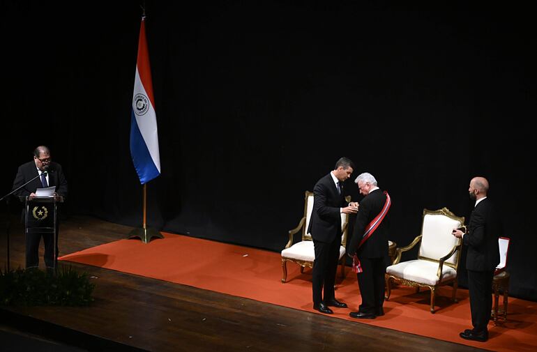 El presidente Santiago Peña coloca la medalla de reconocimiento al maestro Luis Szarán, durante el acto celebrado en el Teatro Municipal "Ignacio A. Pane".