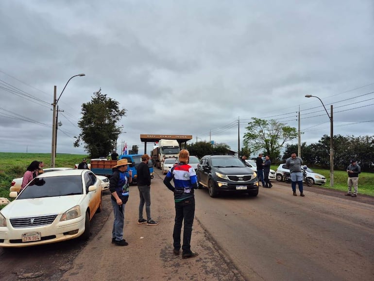 Grupo de diez personas en la ruta PY06, algunos de pie y otros cerca de una camioneta, en un día nublado.