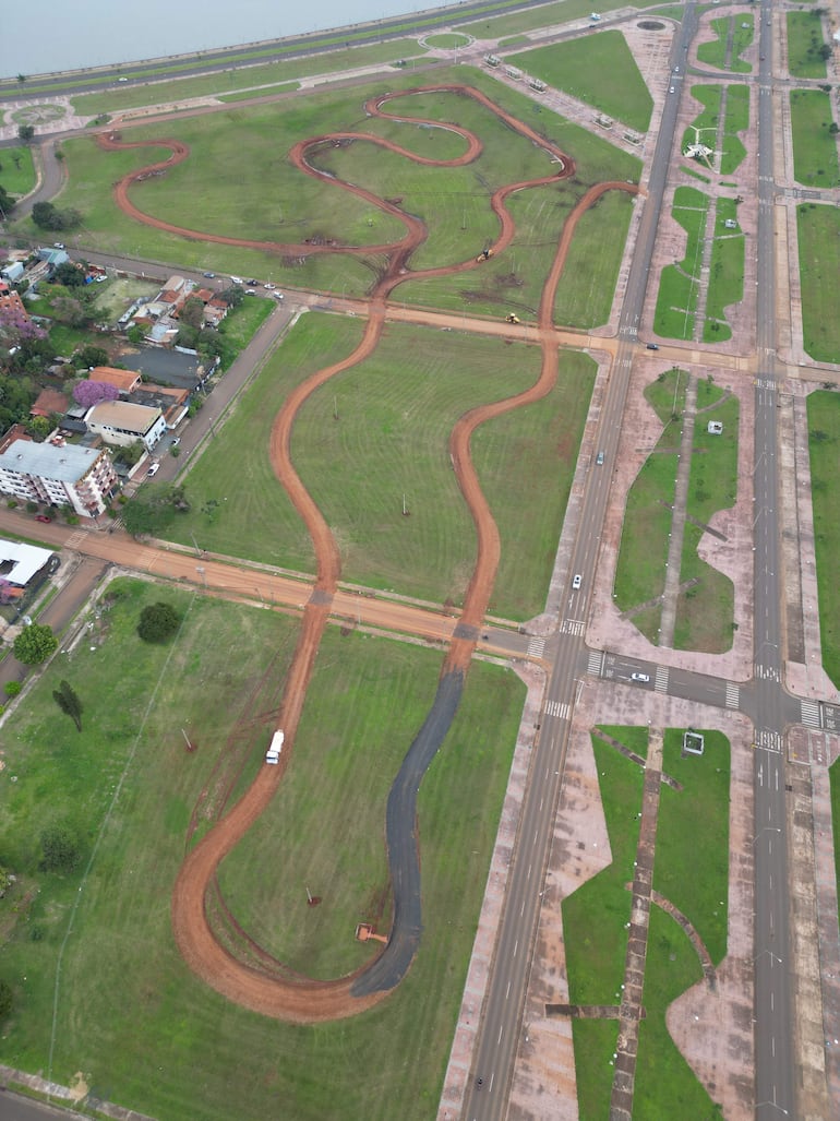 Vista aérea de un área en construcción con caminos curvos en un entorno urbano cercano y clima nublado.