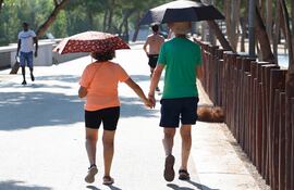 Una pareja paseaba protegida por paraguas en la mañana del martes, en la que el calor ya era fuerte en Madrid y otras zonas. EFE