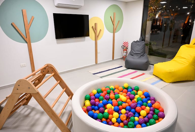 Ambiente recreativo colorido con área de juegos de madera y pelotas de colores, sin presencia de personas.