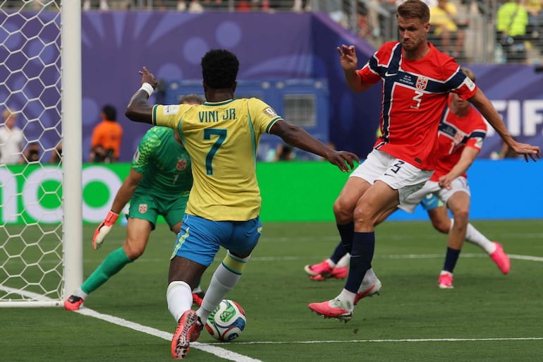 El delantero de Brasil Vinicius Junior corre con el balón dejando en el camino al defensor de Noruega Kristoffer Vassbakk Ajer y al arquero Orjan Nyland durante el partido de octavos de final de la Copa Mundial de la FIFA 2026 entre Brasil y Noruega en el New York/New Jersey Stadium en East Rutherford.