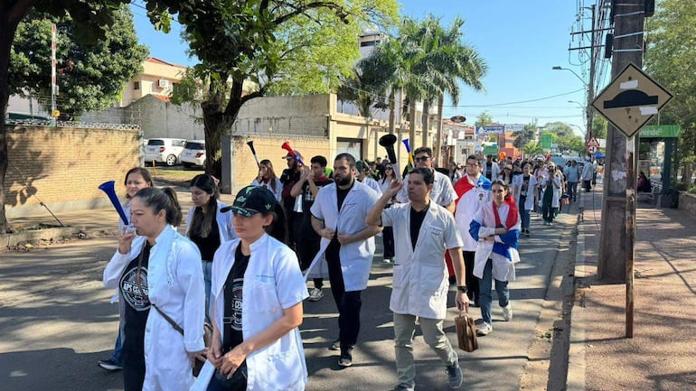 Grupo de 40 personas, principalmente en camisetas blancas, marchan con vuvuzelas en Avenida Venezuela.
