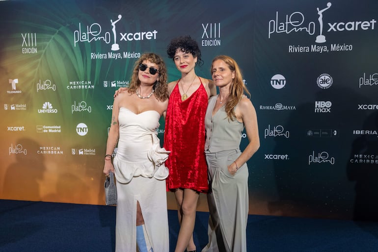 Dolores Fonzi en vestido blanco, Camila Plaate en rojo y Leticia Cristi en traje gris, posando felices en un evento formal.