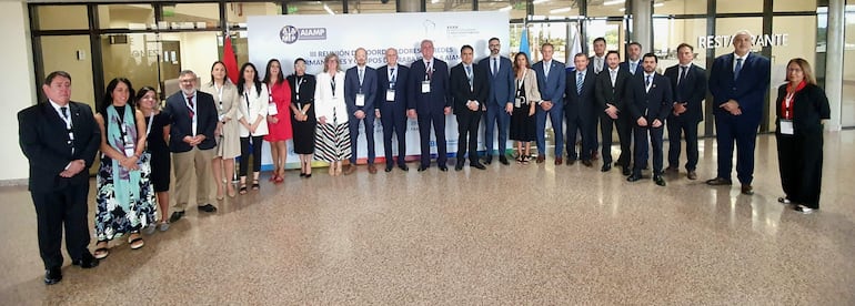 Emiliano Rolón Fernández y Manuel Doldán Breuer en traje formal, junto a otros participantes en ambiente de conferencias, posando frente a un cartel.