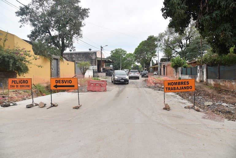 Señales de tráfico en una calle en construcción, con clima nublado y vallas de seguridad delimitando el área.