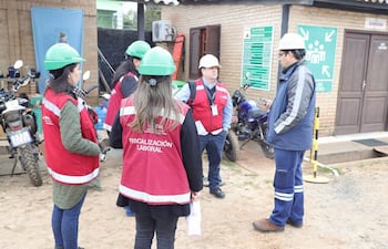 Grupo de fiscalizadores en chalecos rojos conversan en exterior con teléfonos, junto a motocicletas y señalización de emergencia.