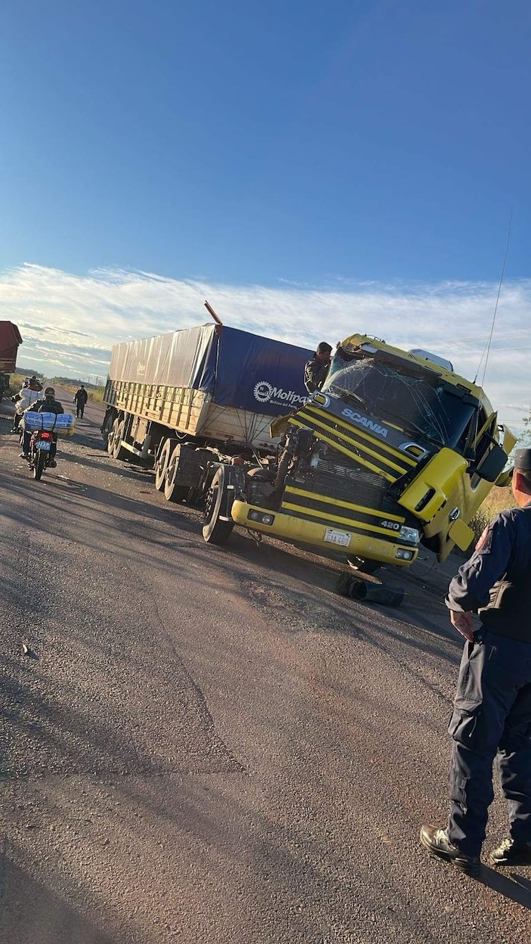 Hombre de negro inspecciona un camión volcado, con otra persona arriba del vehículo. Motocicleta y curiosos al fondo en carretera rural.