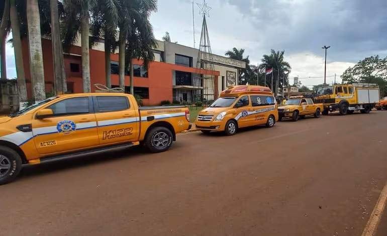 Fila de vehículos de emergencia, incluyendo camionetas y ambulancias, estacionados en una calle sin personas presentes.