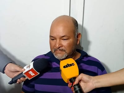 Víctor Raúl De la Cruz, con camiseta de rayas, sentado entre micrófonos de ABC y SNT, luce pensativo en entrevista.