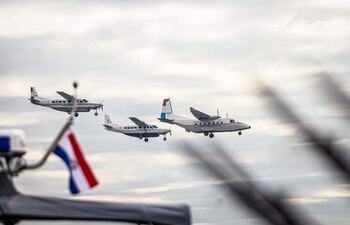 Aviones en vuelo alineados, uno con el diseño 'Poder Judicial de Paraguay', sobre un cielo nublado.