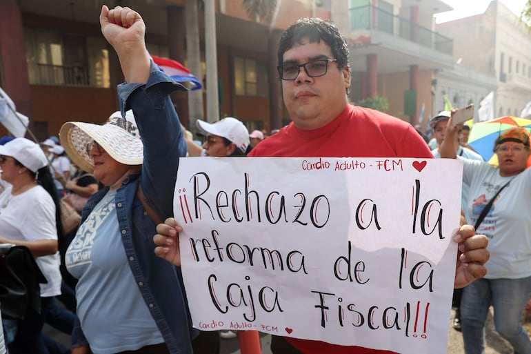 AME2169. ASUNCIÓN (PARAGUAY), 05/02/2026.- Una persona sostiene un cartel en una marcha en rechazo a la ley de jubilaciones este jueves, en Asunción (Paraguay). EFE/ Juan Pablo Pino
