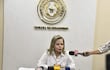 Lilian Samaniego en camisa blanca habla ante varios micrófonos en una sala de prensa con el escudo nacional al fondo.