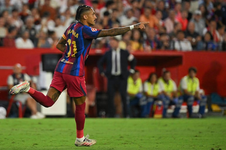 El delantero brasileño del Barcelona, Raphinha, lo celebra tras marcar un gol durante el partido de fútbol de la liga española entre el Sevilla FC y el FC Barcelona en el estadio Ramón Sánchez Pizjuán de Sevilla.