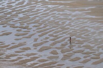 Una mujer camina por la playa de Los Locos este viernes en la localidad cántabra de Suances.