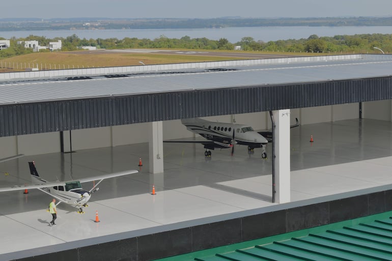Persona con chaleco reflectante camina cerca de dos aeronaves dentro de un hangar en ambiente ordenado y funcional.