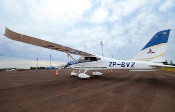 Avión ZP-BVZ de colores blanco y azul, estacionado en pista de aterrizaje, sin personas visibles, con cielo nublado de fondo.