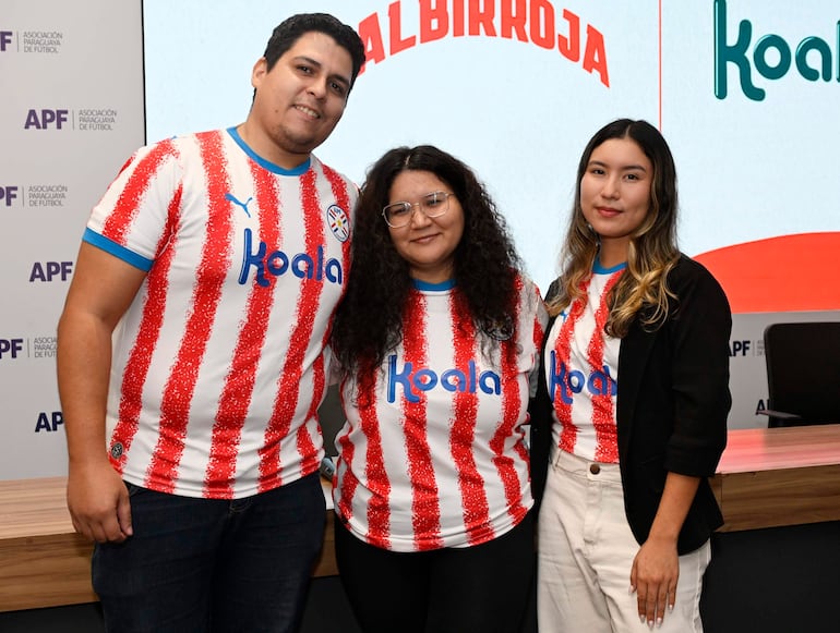 Mujer con vestimenta de selección paraguaya y hombre con chaqueta azul en evento formal de Koala y la APF, con logo de Albirroja visible.