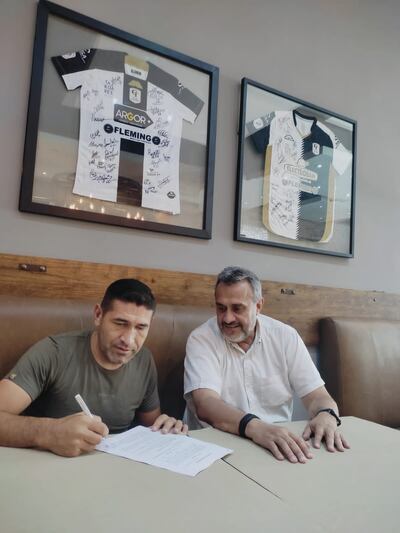 El zaguero Luis Cabral estampa la firma que lo vincula por un año más con Tacuary, a su lado el vicepresidente Guillermo "Nito" Vera.