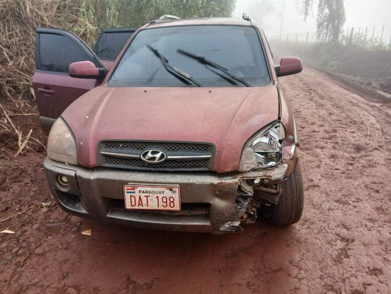 SUV Hyundai rojo con daños visibles en un camino rural, rodeado de vegetación densa y condiciones de neblina.