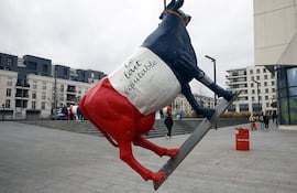Una vaca pintada con los colores de la bandera nacional francesa con las palabras 'Leche de comercio justo' se exhibe durante una protesta de agricultores de sindicatos de la agricultura y la industria láctea contra el acuerdo UE-Mercosur, afuera de la sede de Lidl en el suburbio de Chatenay-Malabry, al suroeste de París.