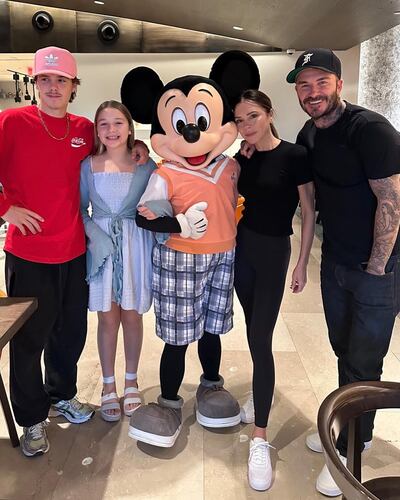 David y Victoria Beckham con sus hijos menores Cruz y Harper posando con Mickey.