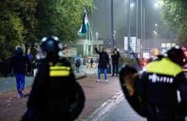 Un partidario ondea una bandera palestina frente a agentes de policía de la Unidad Móvil (ME) durante una manifestación pro palestina al margen del partido de fútbol de la Liga Europea de la UEFA entre el Ajax Amsterdam y el Maccabi Tel Aviv, en Amsterdam.