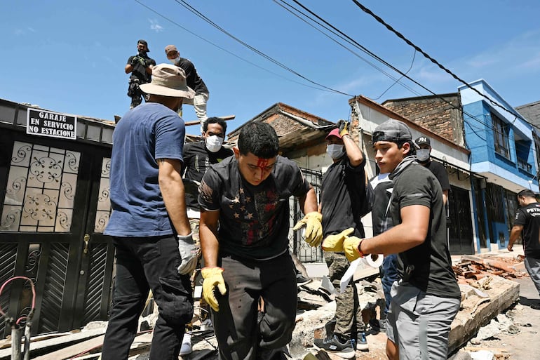 Un joven herido y sangrando sale de una casa derrumbada durante las labores de limpieza de escombros tras un terremoto en Pereira, Colombia