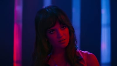 Sophie Thatcher con expresión serena, iluminada por luz suave, vestida de manera elegante en un ambiente cinematográfico.