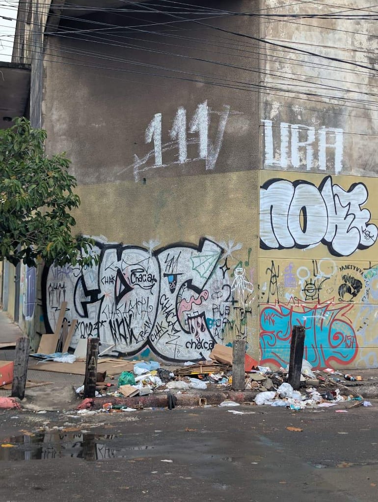 Pared adornada con grafitis coloridos y acumulación de basura en el suelo, en una calle de Asunción.