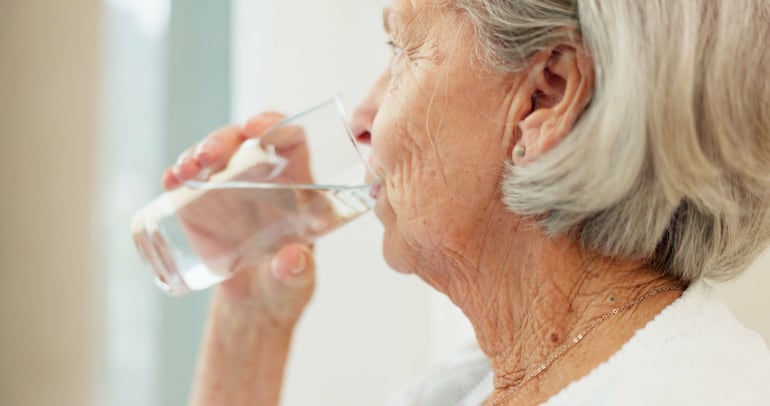 Adulto mayor bebe agua.