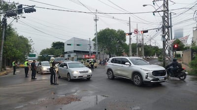 Agentes de policía en uniforme dirigen el tráfico en una intersección, con vehículos detenidos y un día nublado.