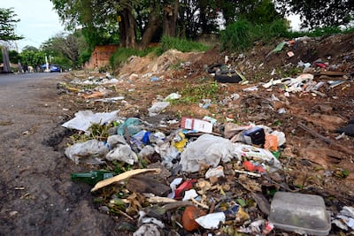Zona residencial descuidada con basura acumulada, incluyendo plásticos y vegetación, que muestra abandono ambiental.