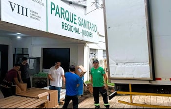 Hombres trasladando cajas de cartón en el Parque Sanitario de Misiones, concentrados en su tarea de entrega de medicamentos.