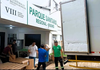 Hombres trasladando cajas de cartón en el Parque Sanitario de Misiones, concentrados en su tarea de entrega de medicamentos.
