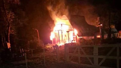 Construcción rural en llamas, iluminada por el fuego y generando intensa humareda en medio de la noche.