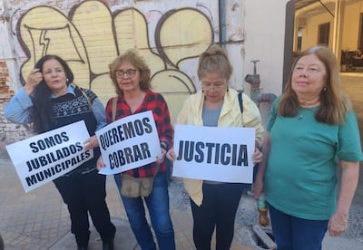 Cuatro mujeres jubiladas con pancartas en una manifestación, vestidas con ropa de colores variados, expresiones serias y activas en un entorno urbano.