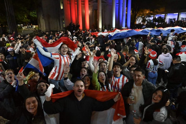 Personas celebrando en la calle Palma, muchas con camisetas de Paraguay y banderas, expresan felicidad y alegría durante la fiesta popular.