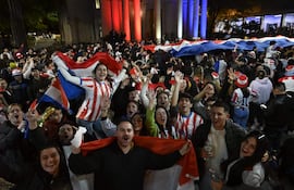Personas celebrando en la calle Palma, muchas con camisetas de Paraguay y banderas, expresan felicidad y alegría durante la fiesta popular.