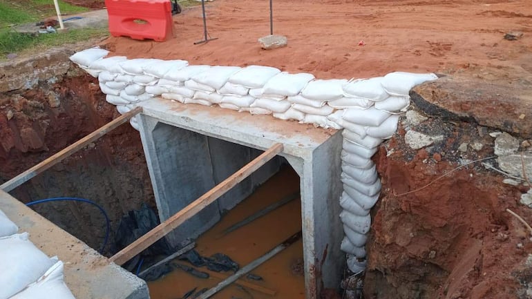 Abertura en construcción en terreno con sacos de arena apilados y estructuras de madera en un entorno de obra.