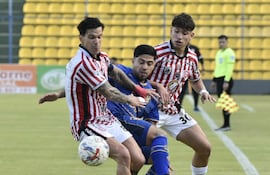 Aldo Quiñónez de San Lorenzo frena la marcha de Sergio "Chico" Díaz detrás se acerca para reforzar la marca Axel Galeano.