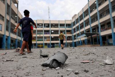 Niños caminan junto a escombros en el patio de una escuela de la Agencia de la ONU para los Refugiados Palestinos afectada por bombardeos palestinos, en la Ciudad de Gaza.