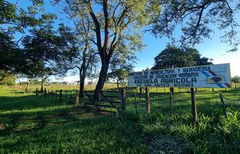 Cartel de madera del Ministerio de Agricultura y Ganadería en un campo verde con árboles al fondo, bajo un cielo despejado.