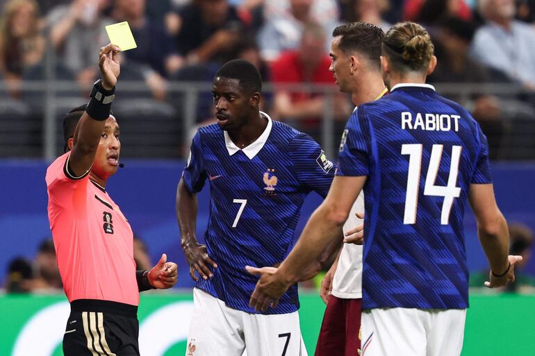 El árbitro salvadoreño Iván Barton muestra una tarjeta amarilla al centrocampista francés #14 Adrien Rabiot durante el partido de semifinales del torneo de fútbol de la Copa Mundial 2026 entre Francia y España en el Dallas Stadium en Arlington.